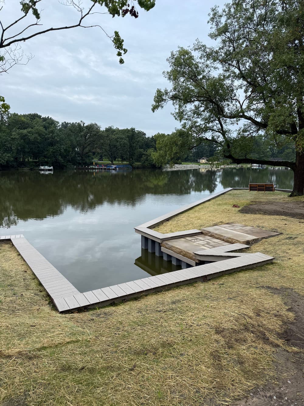 Scenic riverside view featuring a wooden dock and calm water under cloudy skies.