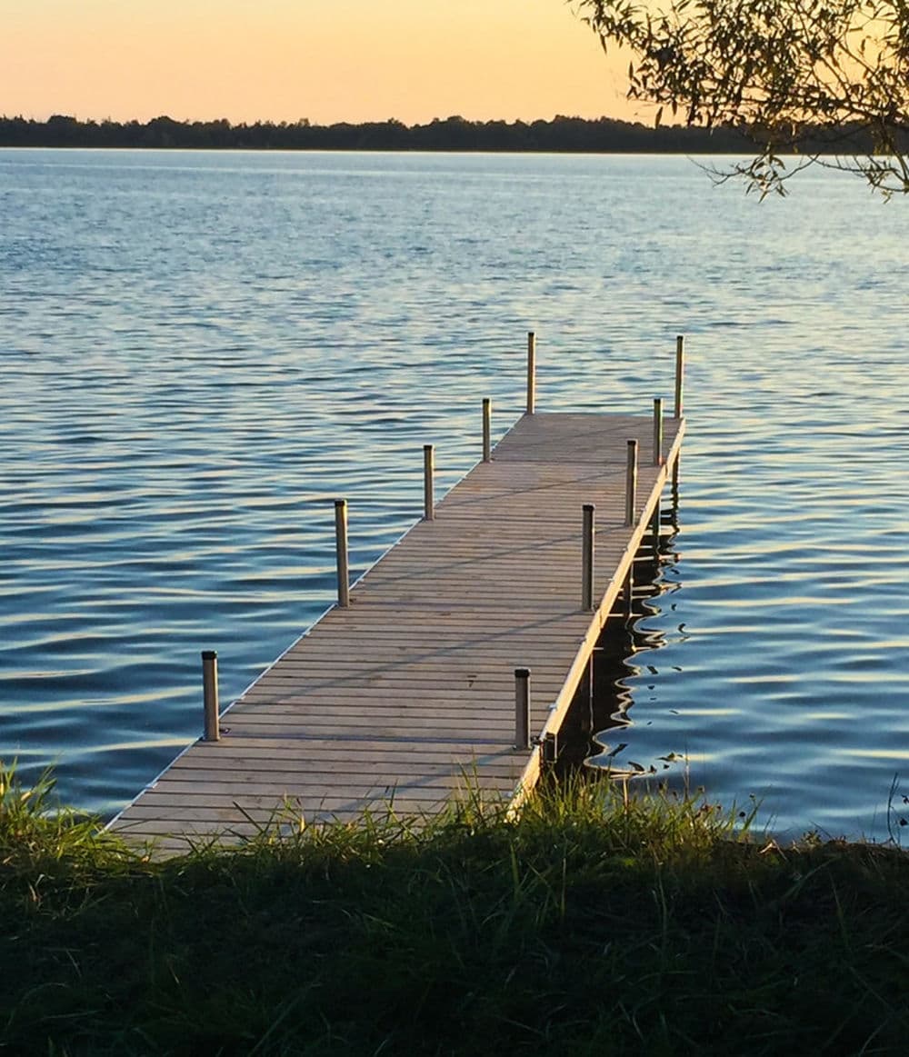 scenic wooden dock extending into calm lake water at sunset
